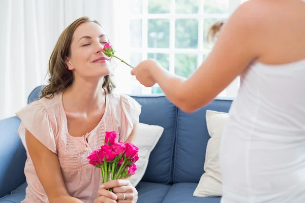 Mãe cheirar flores com criança na sala de estar — Fotografia de Stock