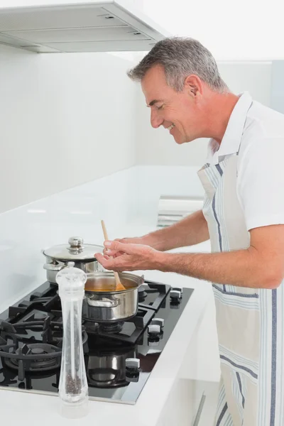 Side view of a smiling man preparing food in kitchen — Stock Photo, Image