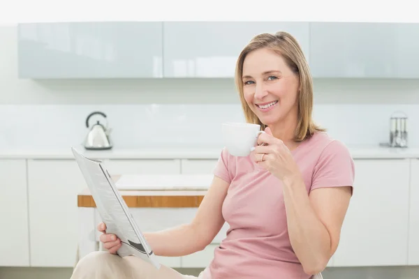 Ontspannen vrouw met krant hebben koffie in keuken — Stockfoto