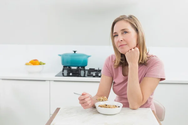 Femme réfléchie ayant des céréales dans la cuisine — Photo