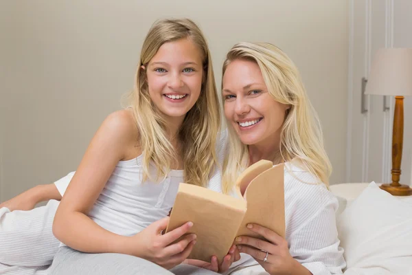 Мать и дочь держат книгу историй в постели — стоковое фото