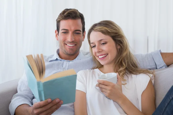 Relaxed young reading book on couch — Stock Photo, Image