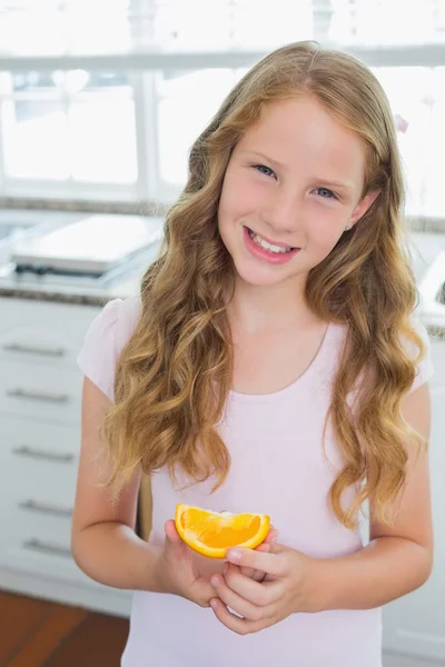 Smiling young girl with a sweetlime slice in kitchen — Stock Photo, Image