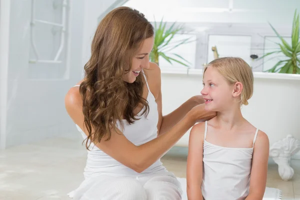 Mujer ajustando el pelo de la niña linda en el baño — Foto de Stock