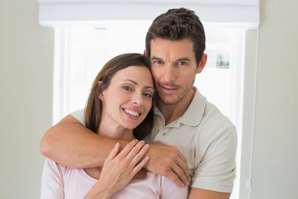 Loving man embracing woman from behind at home — Stock Photo, Image