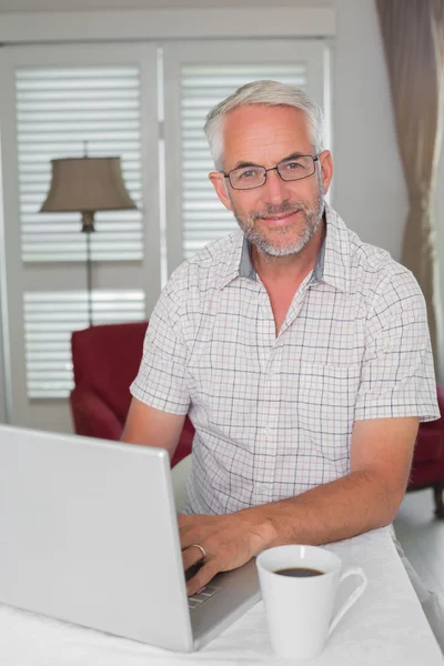 Lachende volwassen man met laptop thuis — Stockfoto