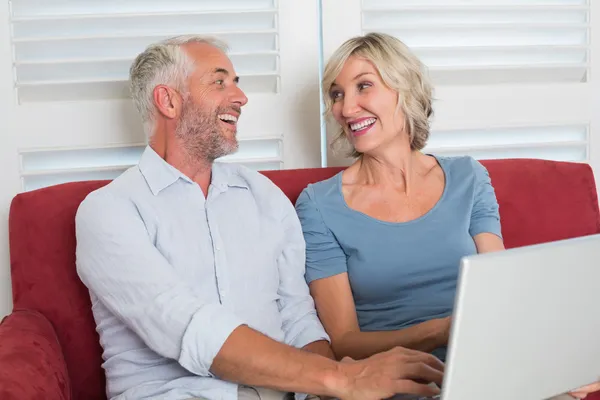 Vrolijke volwassen vrouw en man met laptop in de woonkamer — Stockfoto