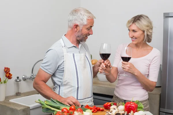 Pareja madura con copas de vino en la cocina — Foto de Stock