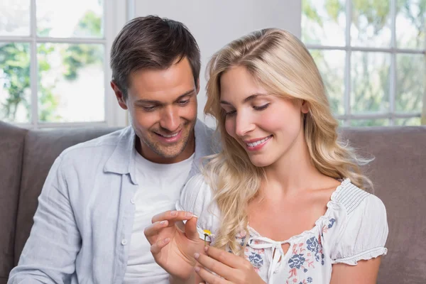 Happy young couple looking at flower in living room — Stock Photo, Image