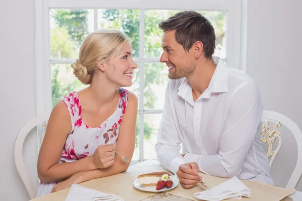 Liebespaar mit Gebäck schaut sich am Esstisch an — Stockfoto