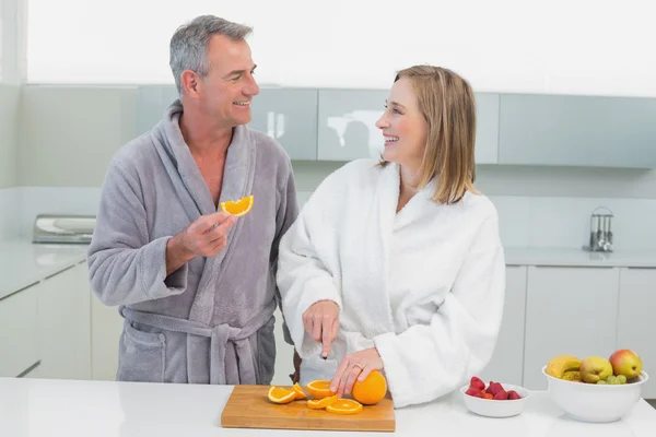 Casal feliz cortando laranja na cozinha — Fotografia de Stock