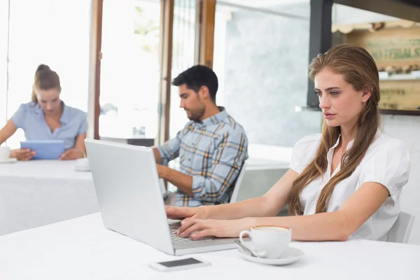 Geconcentreerde vrouw met laptop in koffie shop — Stockfoto