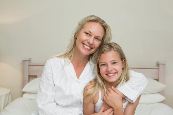 Mother and daughter sitting in bed at home — Stock Photo, Image