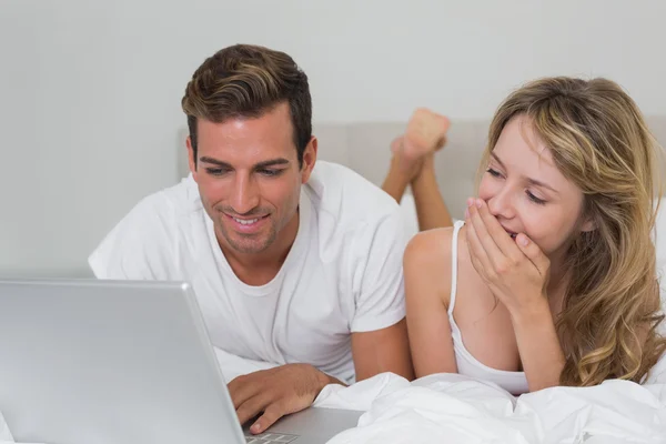 Jeune couple utilisant un ordinateur portable au lit à la maison — Photo