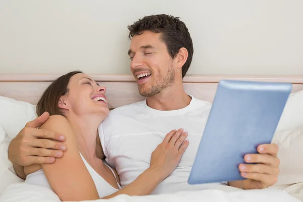 Счастливая пара использует цифровые технологии в постели — стоковое фото