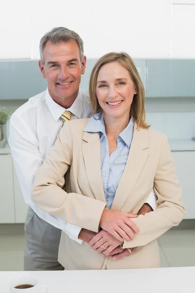 Businessman embracing woman from behind in kitchen — Stock Photo, Image