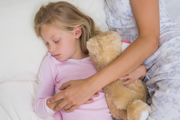 Chica y madre durmiendo pacíficamente con juguete de peluche en la cama —  Fotos de Stock