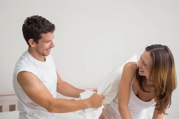 Cheerful couple pillow fighting in bed — Stock Photo, Image