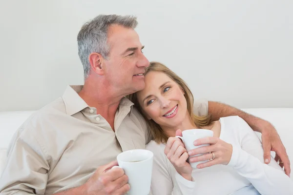 Relaxed loving couple with coffee cups in living room — Stock Photo, Image