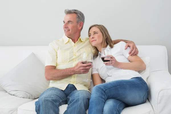 Расслабленная пара с бокалами вина сидя на диване — стоковое фото