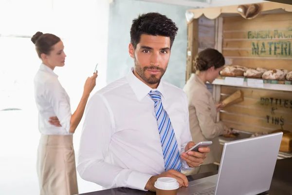 Zakenman met behulp van mobiele telefoon en laptop in office cafetaria — Stockfoto