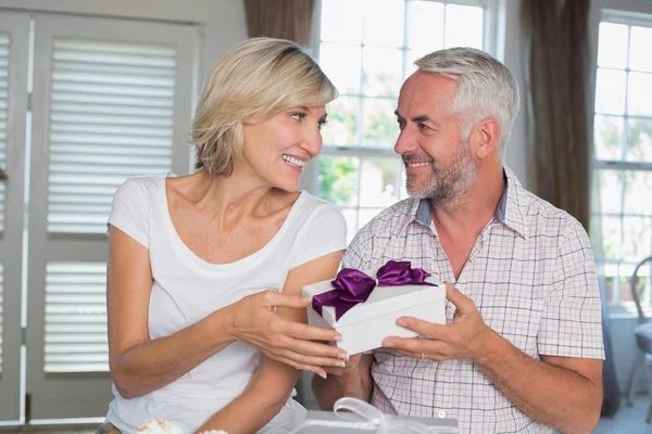Glückliches älteres Paar mit einem Geschenkkarton zu Hause — Stockfoto