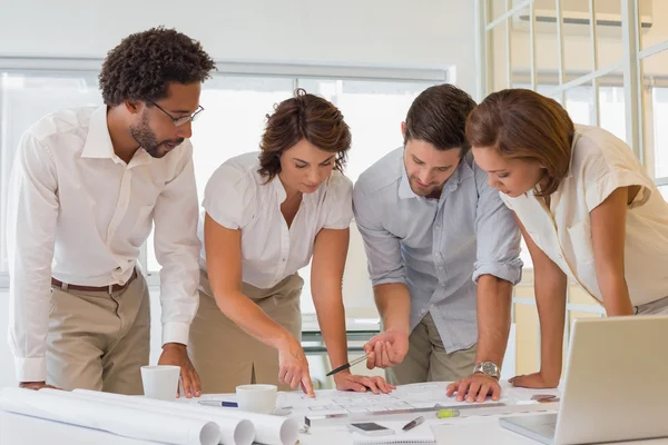 Business people working on blueprints at office