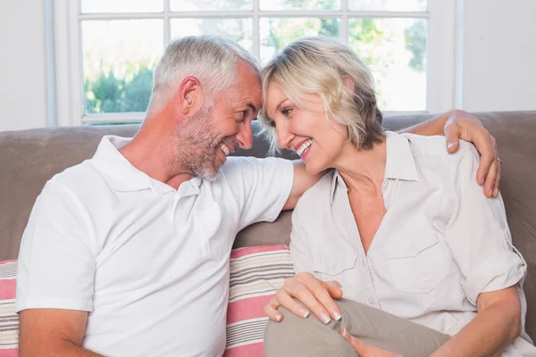 Cheerful mature couple sitting on sofa in living room — Stock Photo, Image