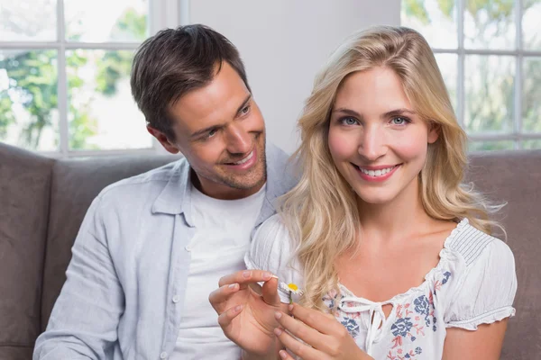 Feliz jovem casal olhando para a flor na sala de estar — Fotografia de Stock