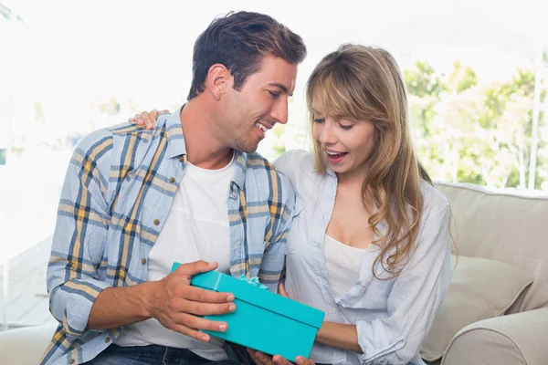 Pareja cariñosa con caja de regalo sentada en el sofá — Foto de Stock