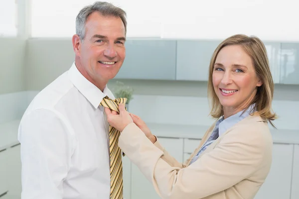 Frau justiert Geschäftsmann-Krawatte in Küche — Stockfoto