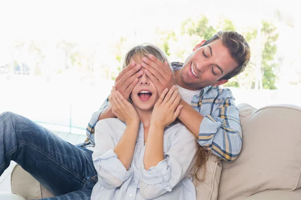 Mann verdeckt glückliche Frauenaugen im Wohnzimmer — Stockfoto