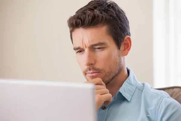 Uomo concentrato utilizzando il computer portatile in soggiorno — Foto Stock