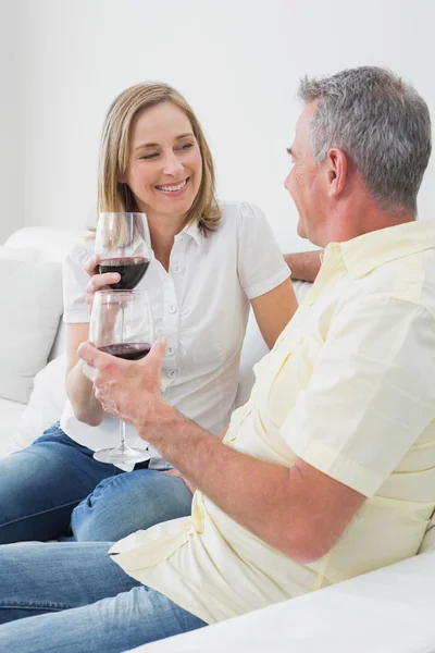 Розслаблена пара з келихами для вина, що сидять на дивані — стокове фото