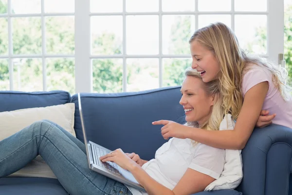 Chica apuntando a la computadora portátil mientras la madre lo usa — Foto de Stock