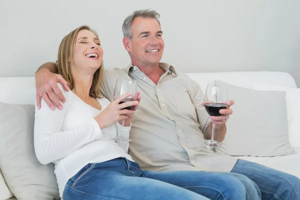 Casal feliz com copos de vinho sentado no sofá — Fotografia de Stock