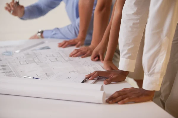 Mid sectie van mensen uit het bedrijfsleven werken op blauwdrukken in office — Stockfoto