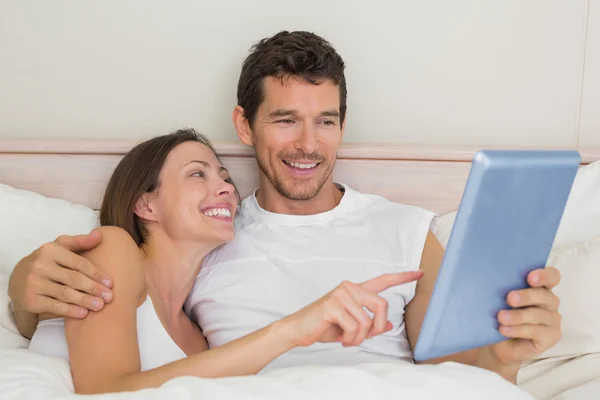 Glückliches Paar mit digitalem Tablet im Bett — Stockfoto