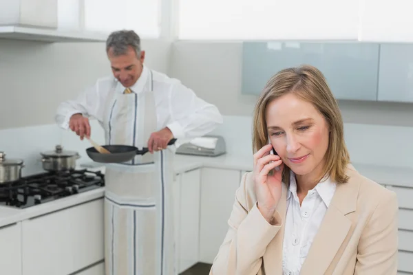 Femme d'affaires sur appel tandis que l'homme prépare la nourriture dans la cuisine — Photo