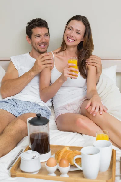 Casal feliz tomando café da manhã na cama — Fotografia de Stock