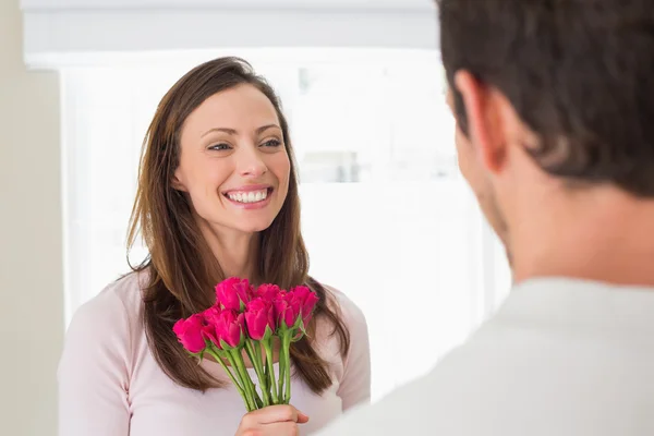 Iloinen nainen katselee miestä kukkia — kuvapankkivalokuva