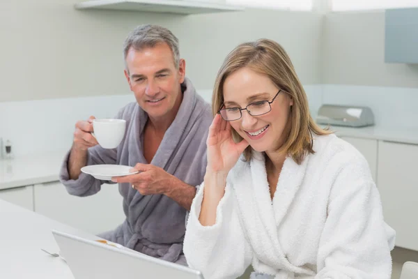 Casal tomando café da manhã ao usar laptop na cozinha — Fotografia de Stock