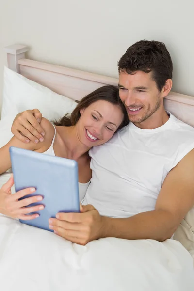 Pareja feliz usando tableta digital en la cama — Foto de Stock