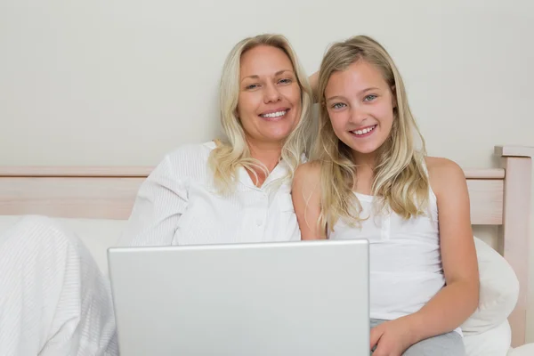 Blond mother and daughter using laptop in bed — Stock Photo, Image