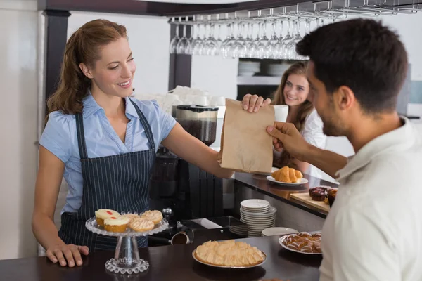 Propietario del café dando comida empaquetada a una pareja en la cafetería — Foto de Stock