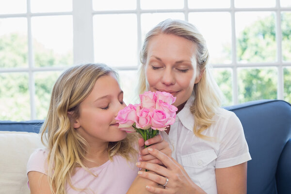 Mother and daughter smelling roses on sofa Royalty Free Stock Images