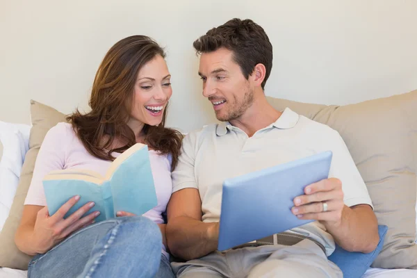 Happy couple with laptop and book on couch — Stock Photo, Image