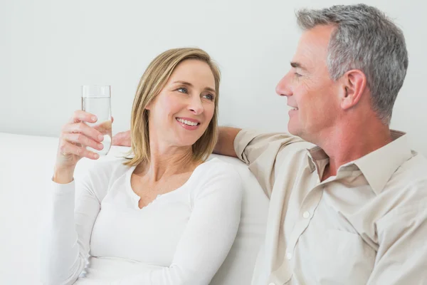 Couple with a glass of water in living room Stock Image