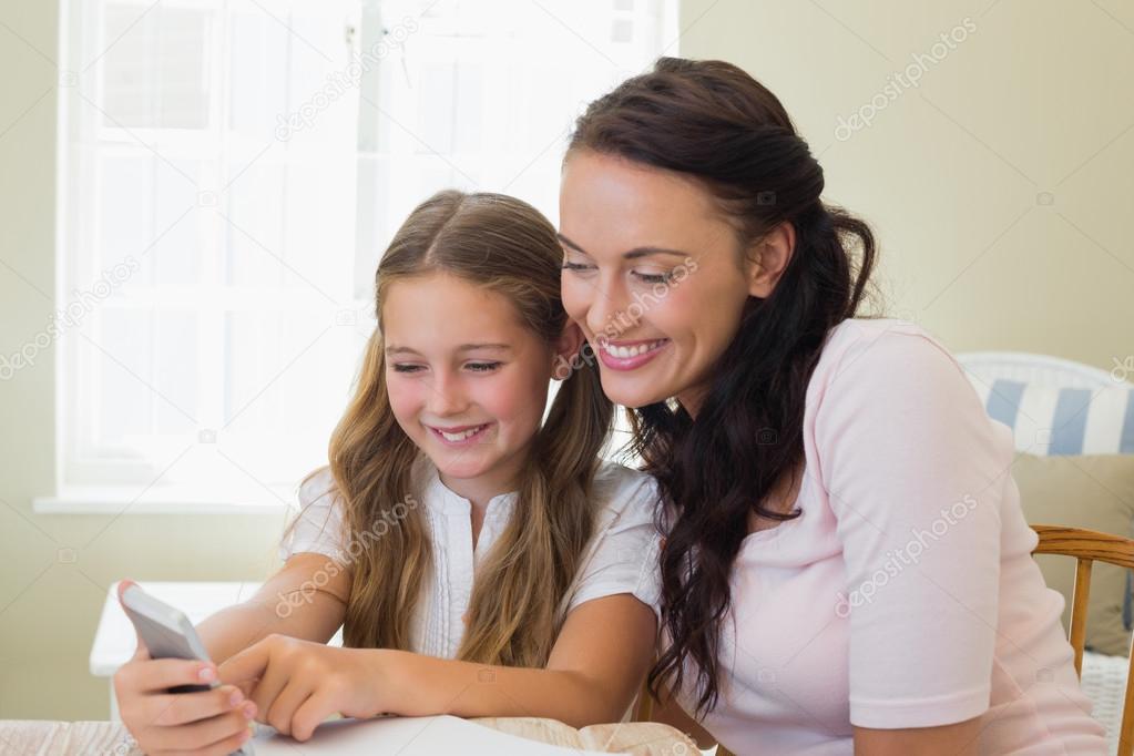 Happy mother and daughter using cell phone
