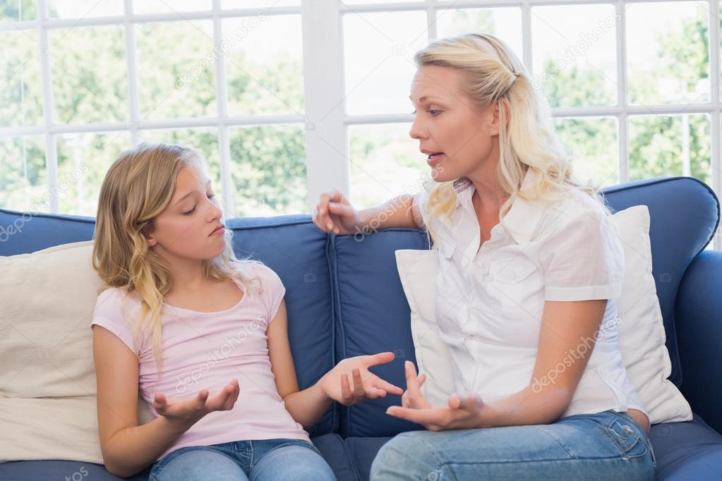 Angry mother scolding daughter on sofa